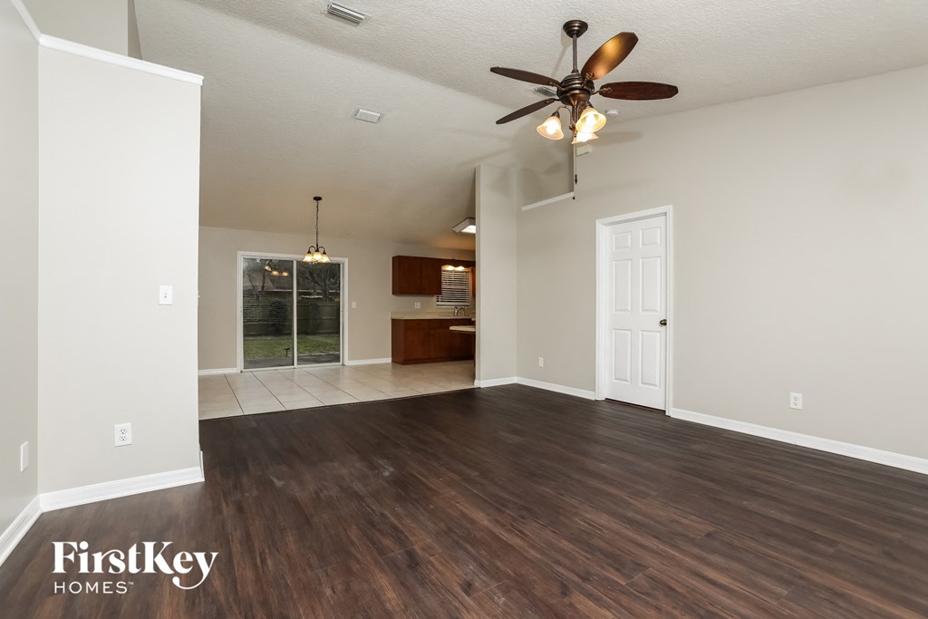 the living room of an empty house with a ceiling fan