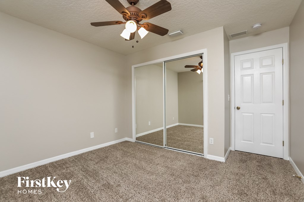 a bedroom with a ceiling fan and a mirrored closet