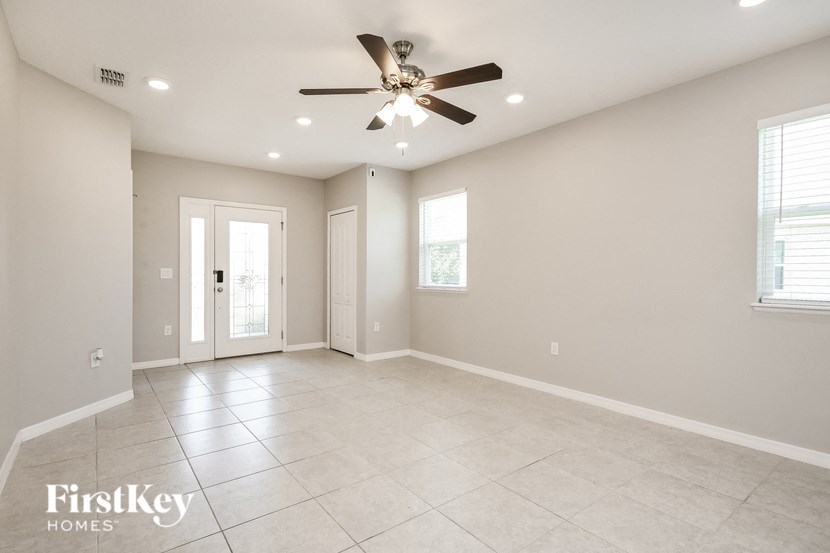 an empty living room with a ceiling fan and tiled floor