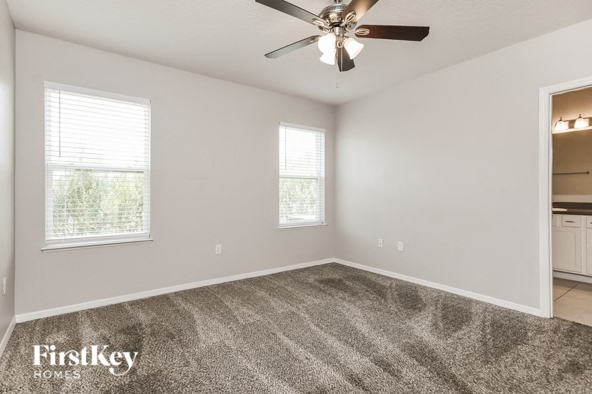 an empty room with a ceiling fan and two windows
