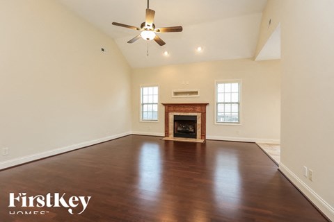 A spacious room with a fireplace and a ceiling fan.
