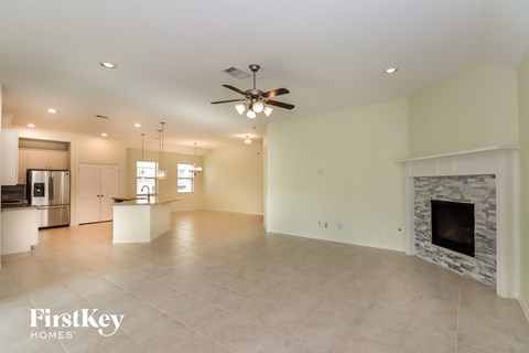 A spacious living room with a fireplace and a ceiling fan.