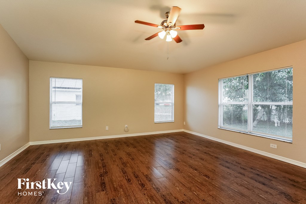 the spacious living room with hardwood floors and a ceiling fan