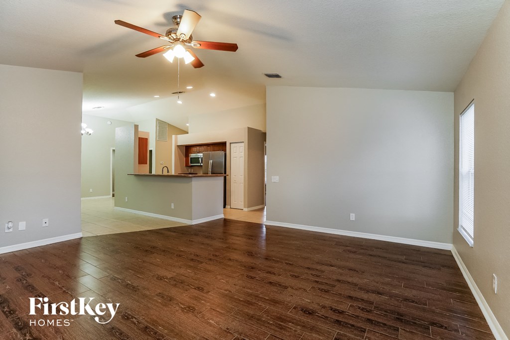 an empty living room with wood flooring and a ceiling fan