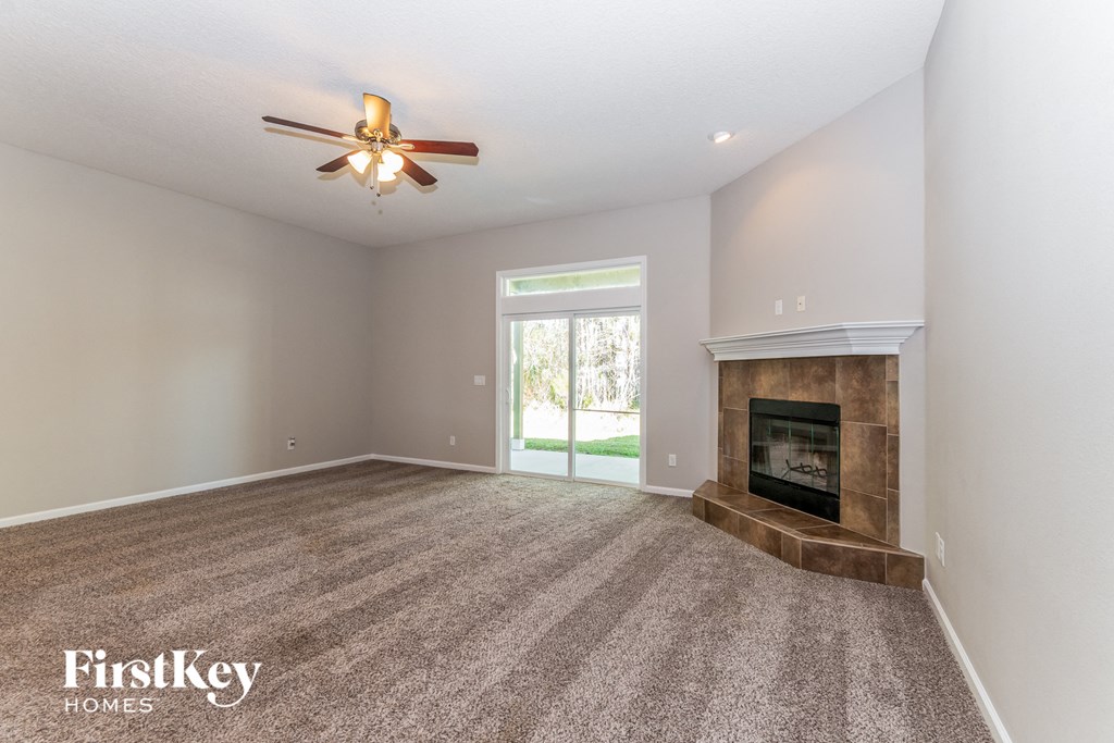A spacious room with a fireplace and a ceiling fan.