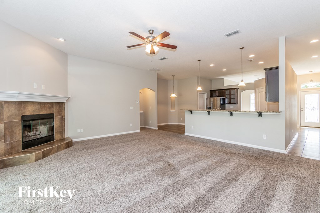 A spacious living room with a fireplace and a carpeted floor.