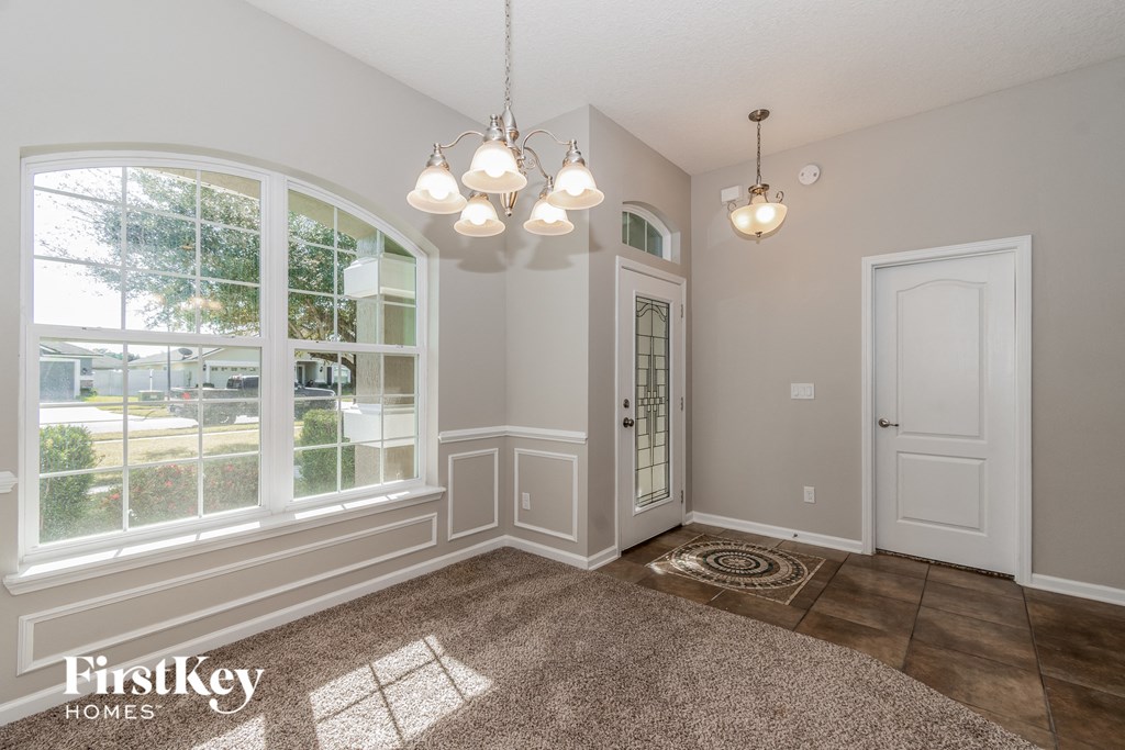 A well-lit room with a rug on the floor and a chandelier hanging from the ceiling.