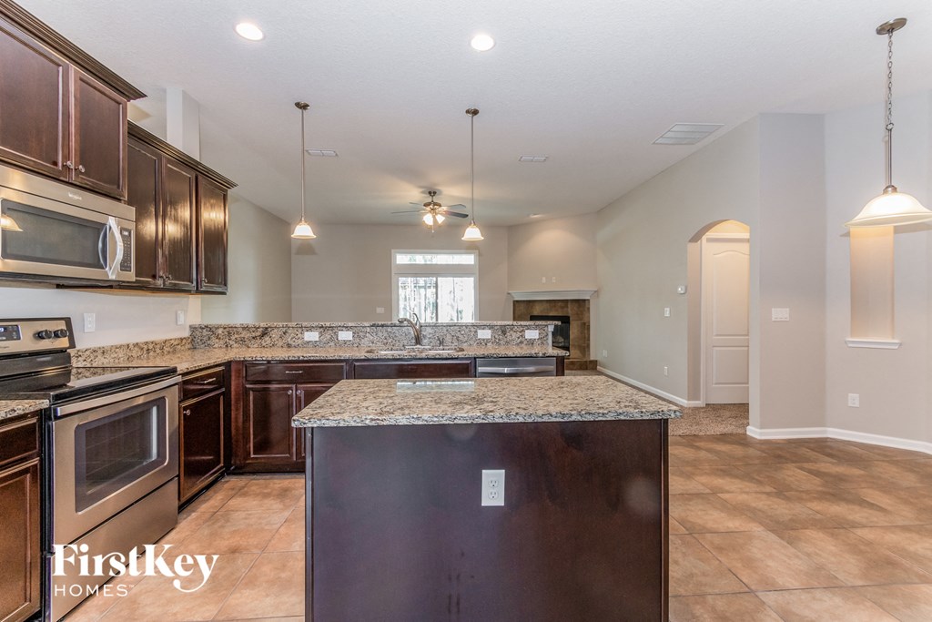 A kitchen with a granite counter top and wooden cabinets.