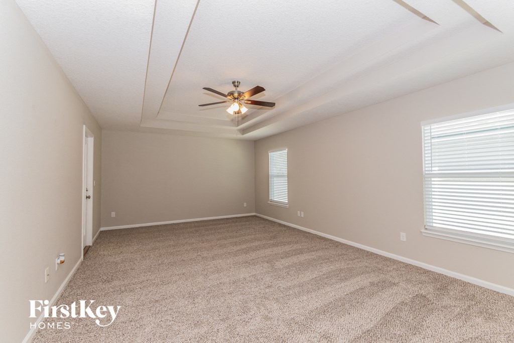 A room with a carpeted floor and a ceiling fan.