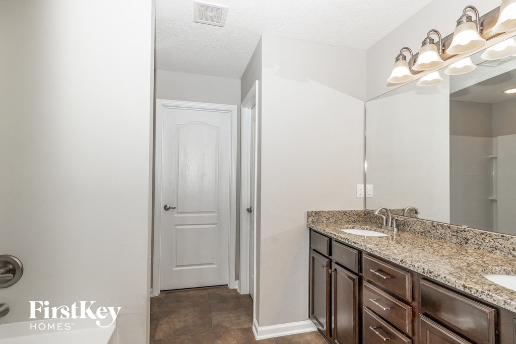 A bathroom with a sink, mirror, and a door.