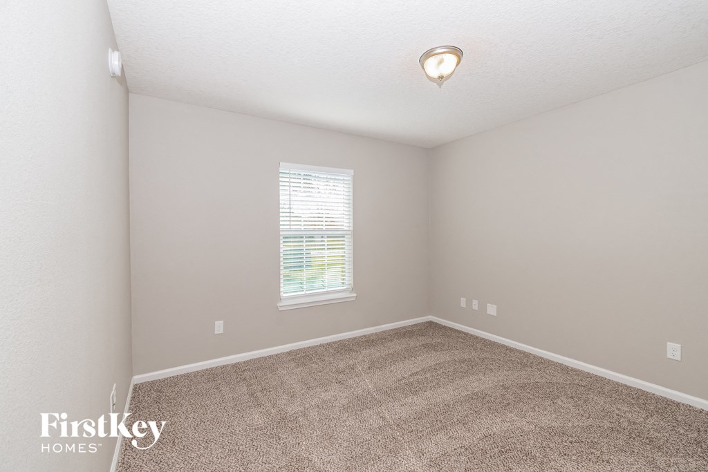 A room with a carpeted floor and a window with blinds.