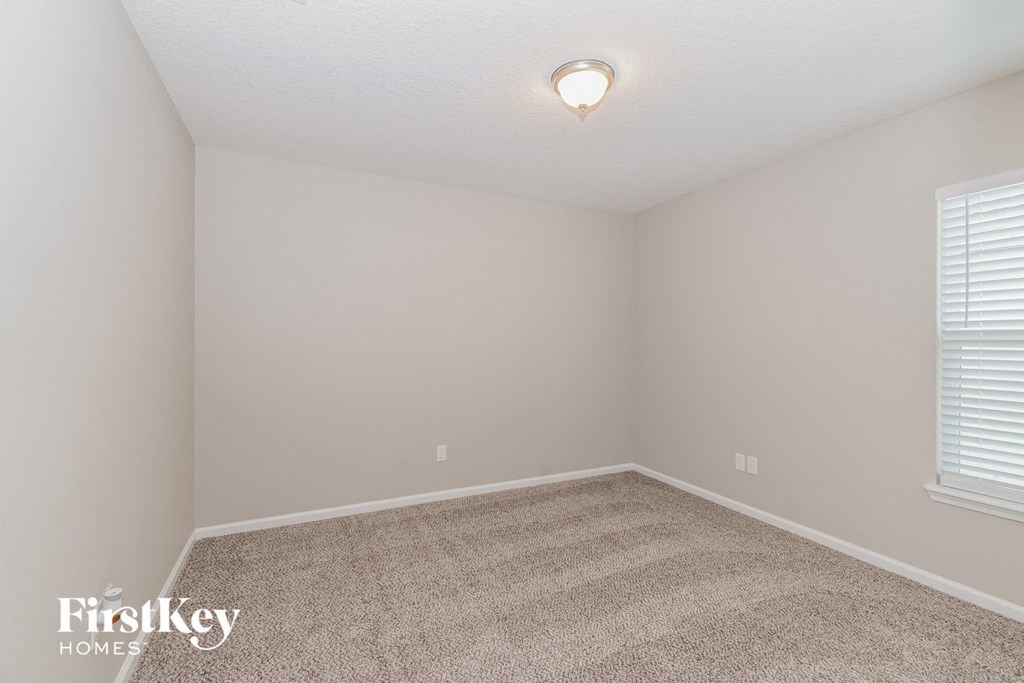 A room with a carpet floor and a window with blinds.