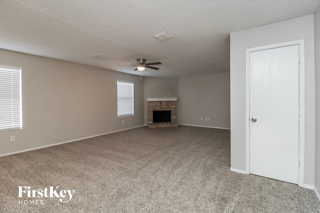 an empty living room with a fireplace and a ceiling fan