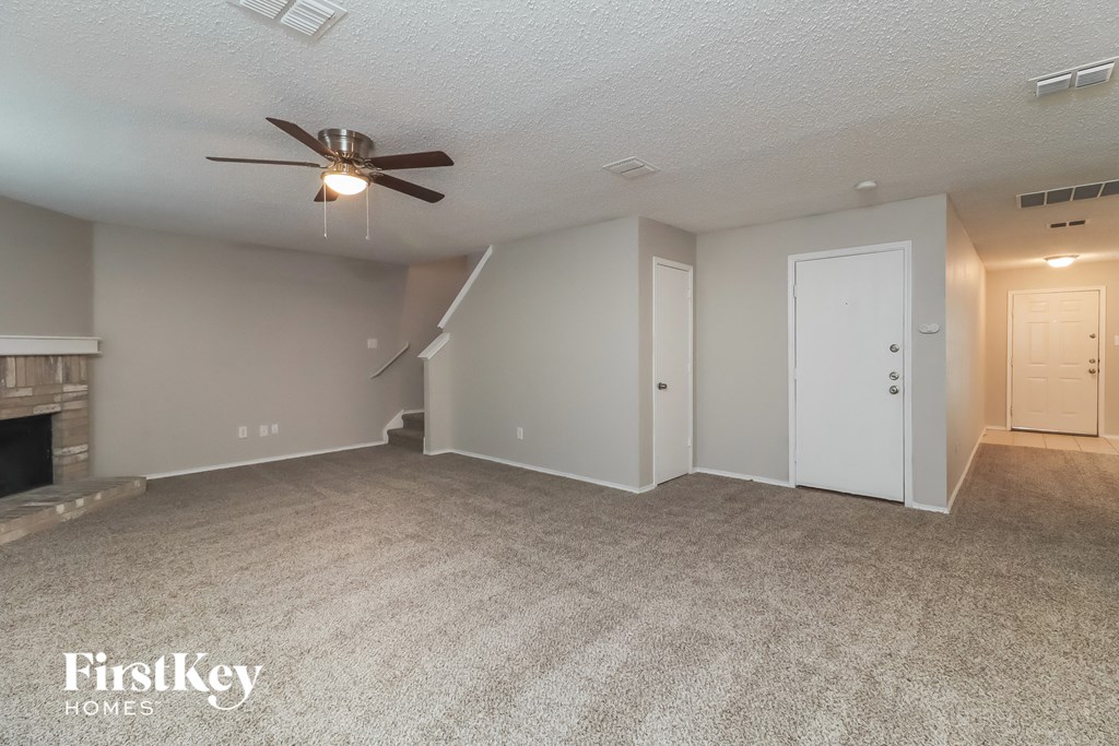 an empty living room with a ceiling fan and a fireplace
