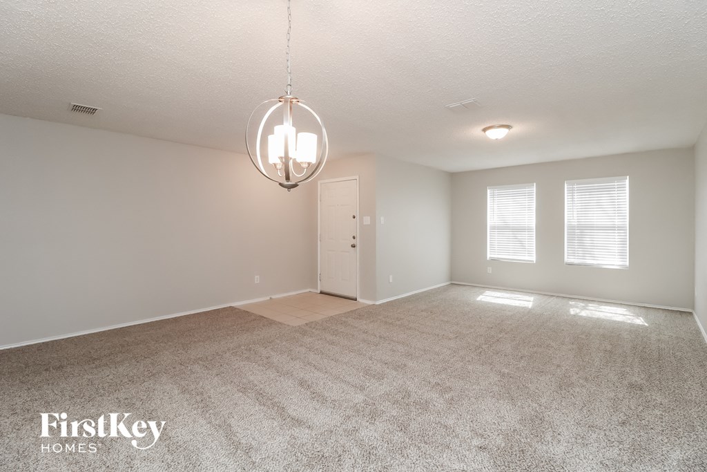 a spacious living room with carpet and a chandelier