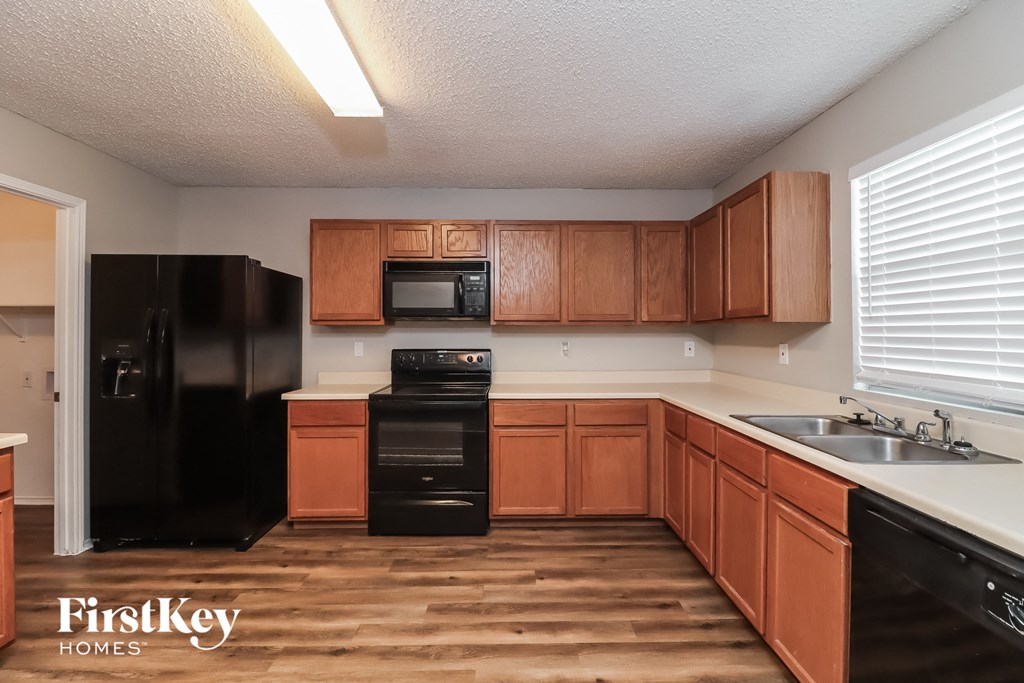 an empty kitchen with wooden cabinets and black appliances