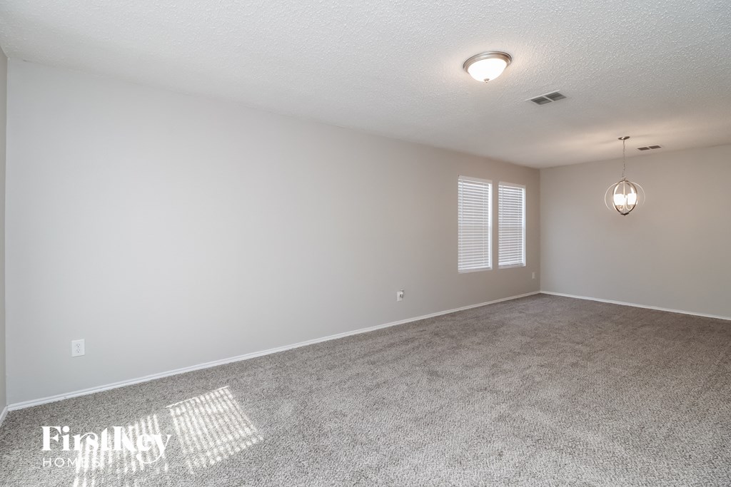 a spacious living room with carpet and white walls