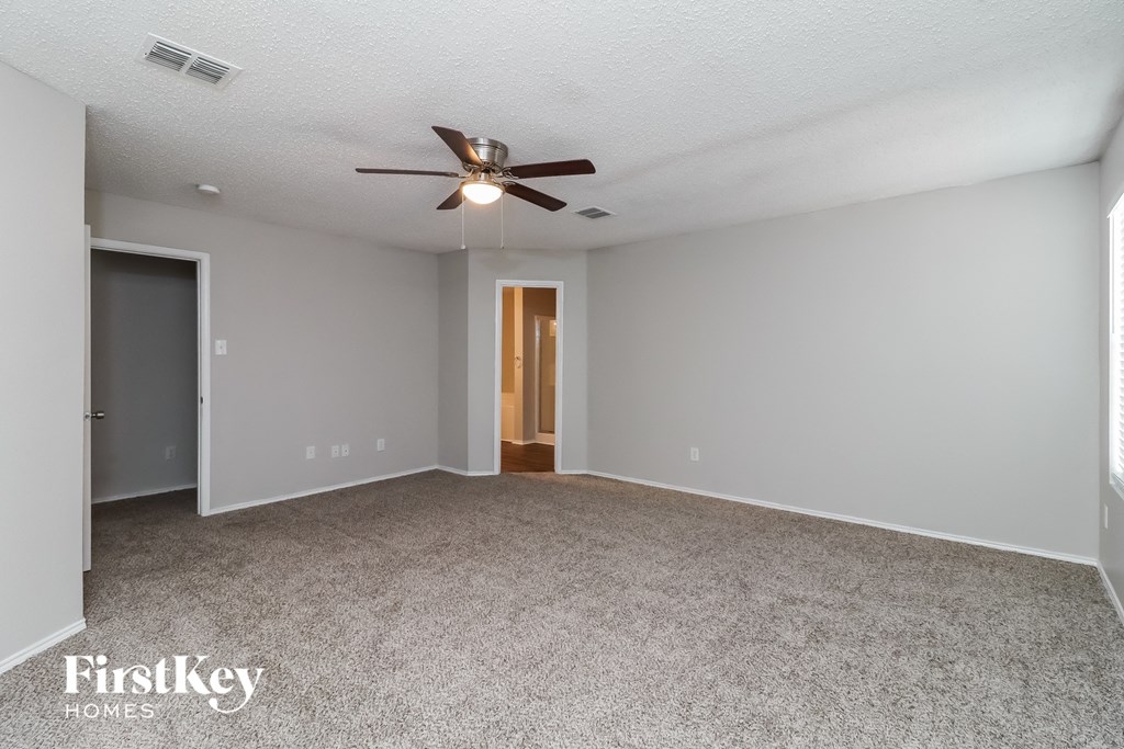 an empty living room with a ceiling fan and gray walls