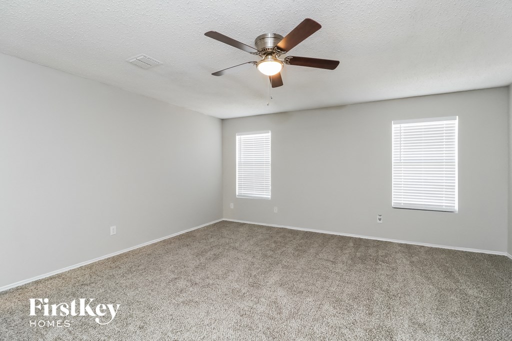 the spacious living room with ceiling fan and carpet