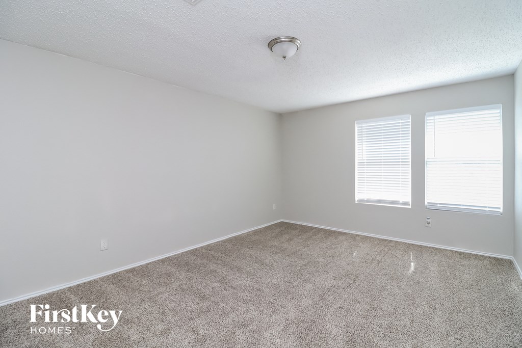 the spacious living room with carpeting and two windows