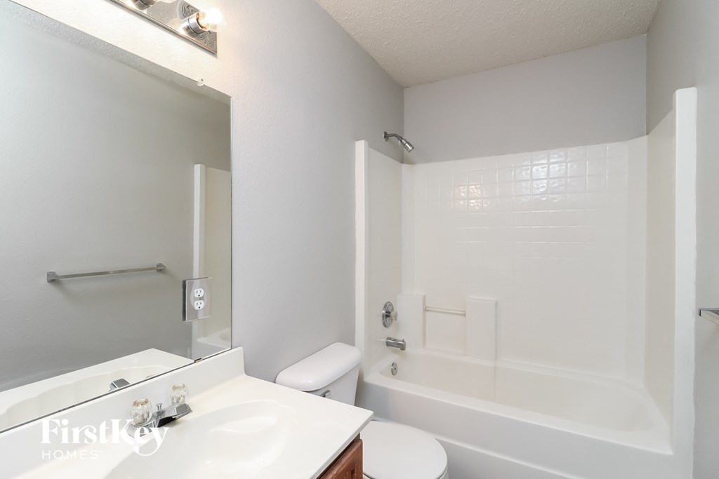 a white bathroom with a tub and a sink and a toilet