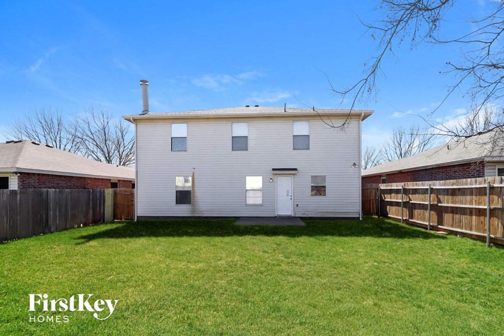 a white house with a backyard and a wooden fence