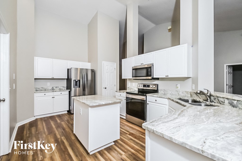 a kitchen with white cabinets and stainless steel appliances and marble counter tops