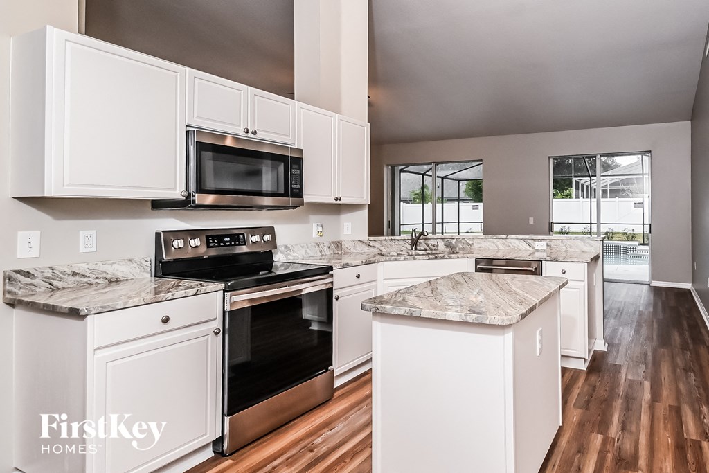 a kitchen with white cabinets and black appliances and marble counter tops