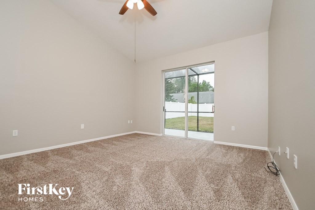 the living room of an empty house with carpet and a ceiling fan