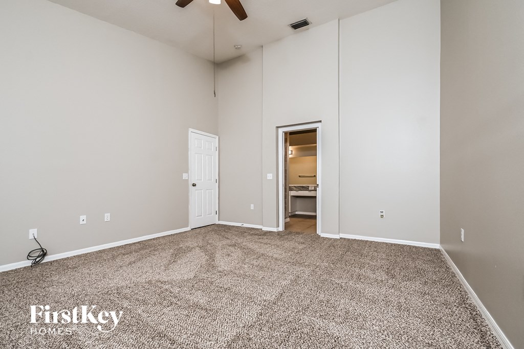 an empty living room with carpet and a door to a bathroom