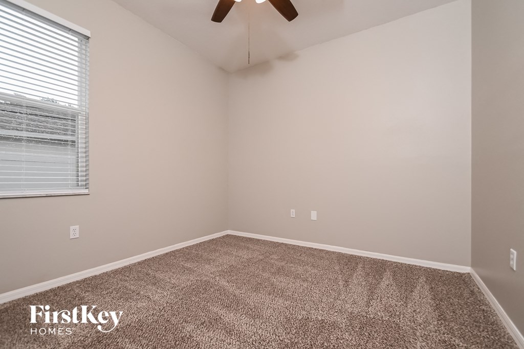 the spacious bedroom with carpeted flooring and a ceiling fan