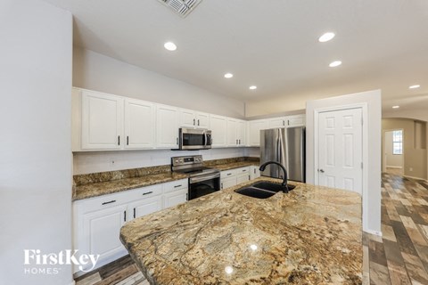 A kitchen with granite countertops and white cabinets.