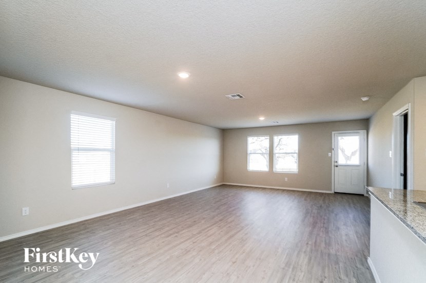 A spacious room with wooden flooring and a large window.