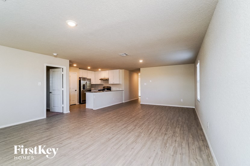 A spacious living room with a kitchen in the background.