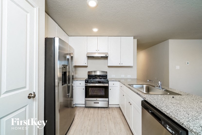 A kitchen with a refrigerator, oven, and sink.