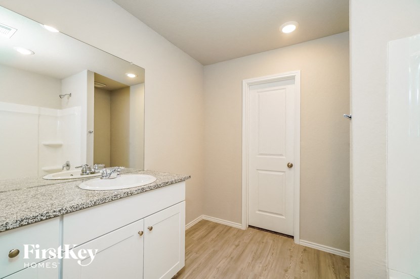 A bathroom with a sink, mirror, and wooden floors.