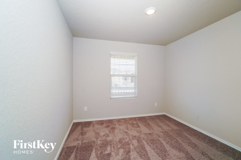 A room with a carpeted floor and a window with blinds.