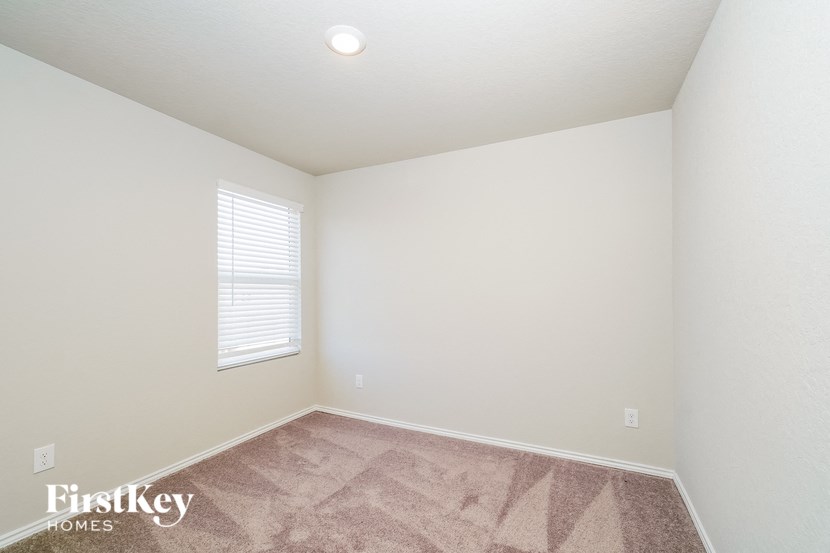 A room with a carpeted floor and a window with blinds.