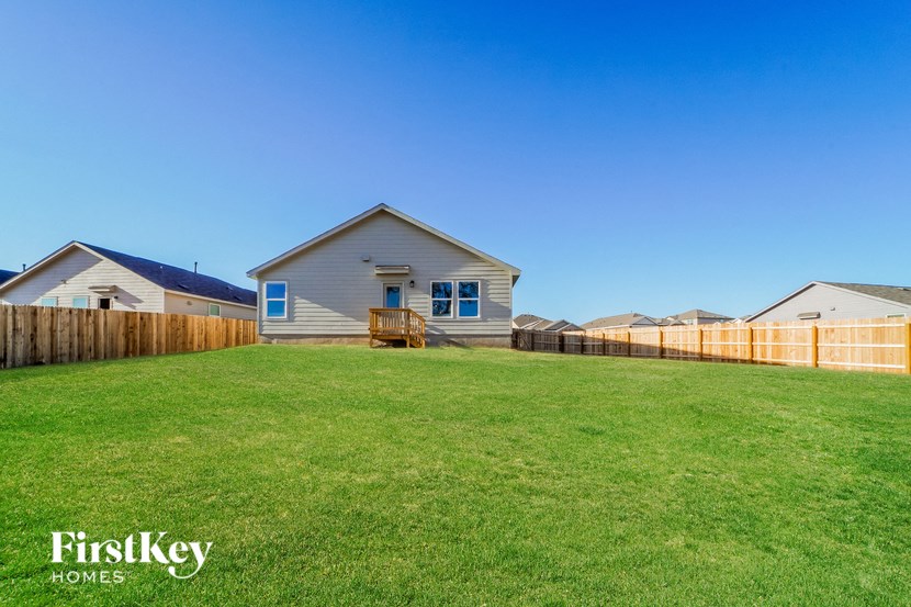 A house with a lawn in front of it and a fence in the background.