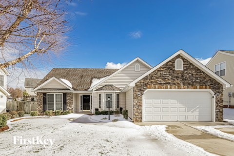 a brick house with a white garage door in the snow