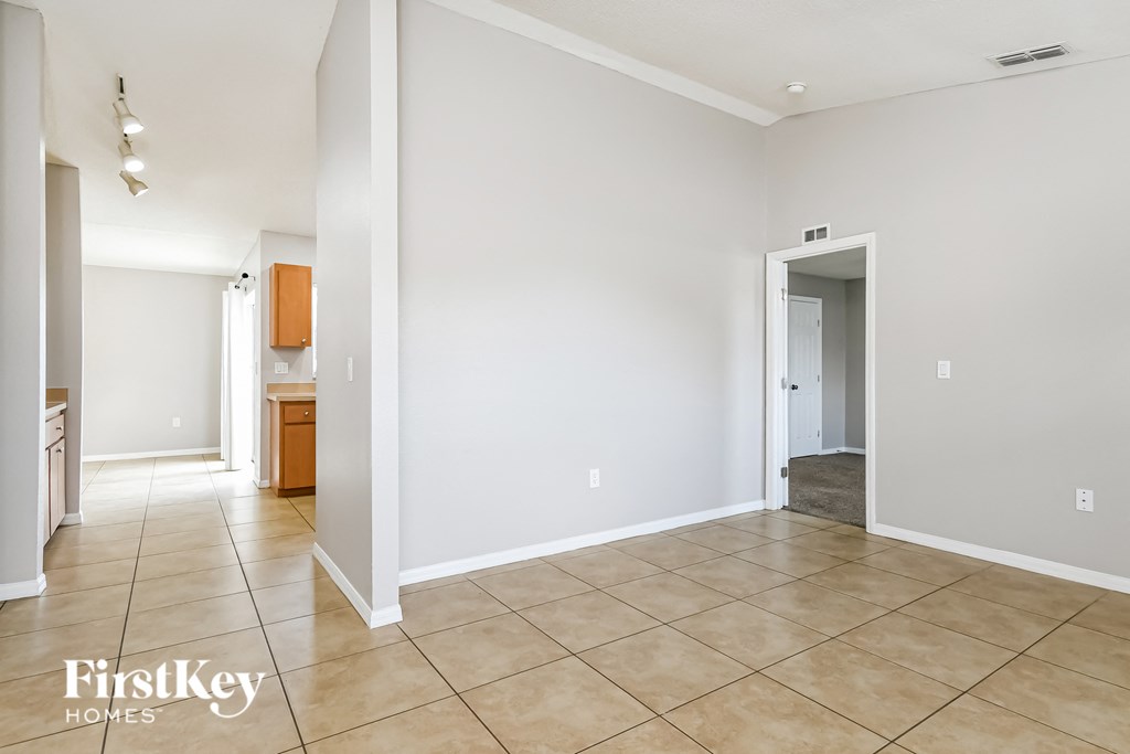 an empty living room with tile flooring and white walls