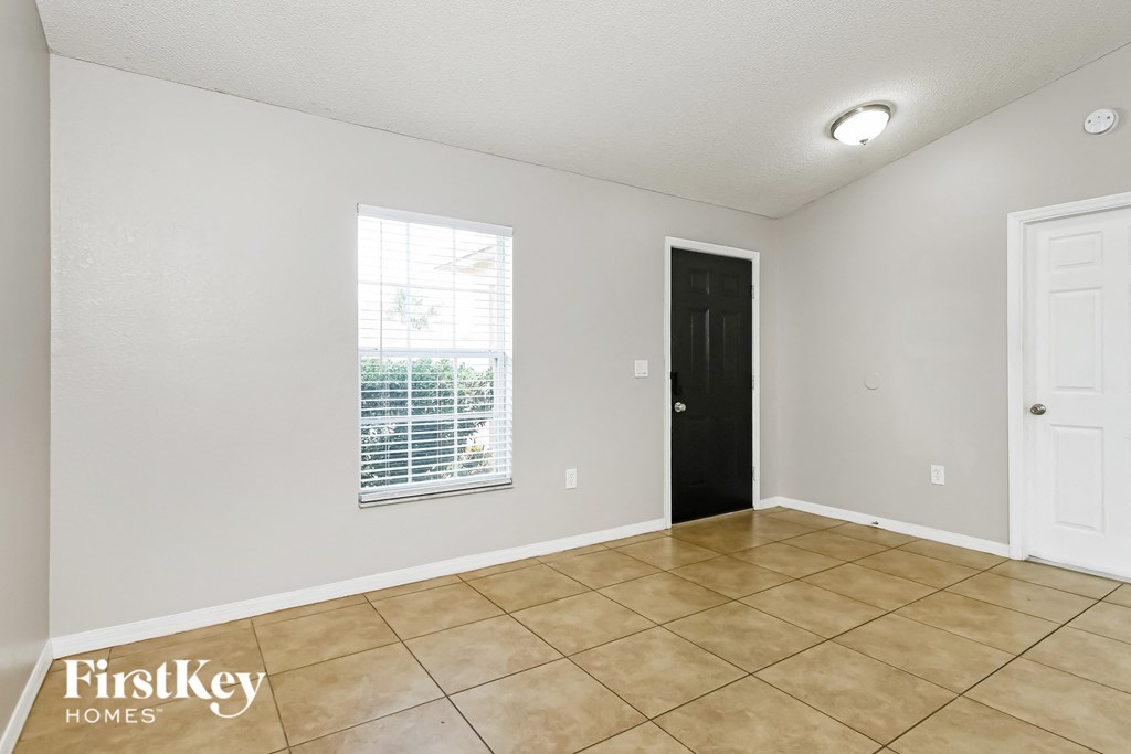 the living room of an empty house with tile flooring and a window