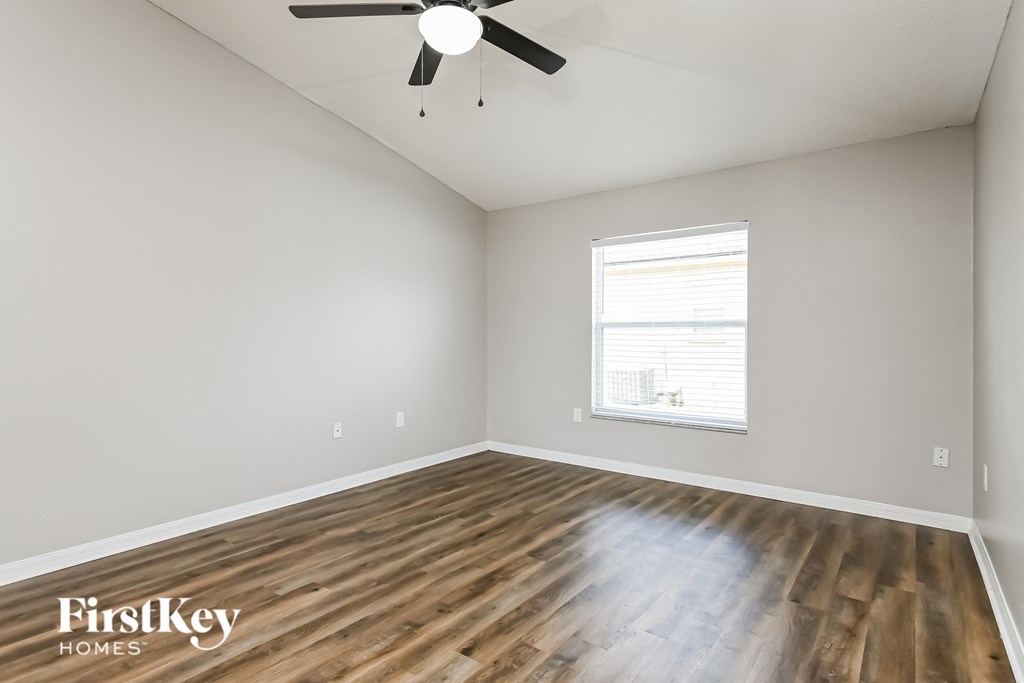 the spacious living room with hardwood flooring and a ceiling fan