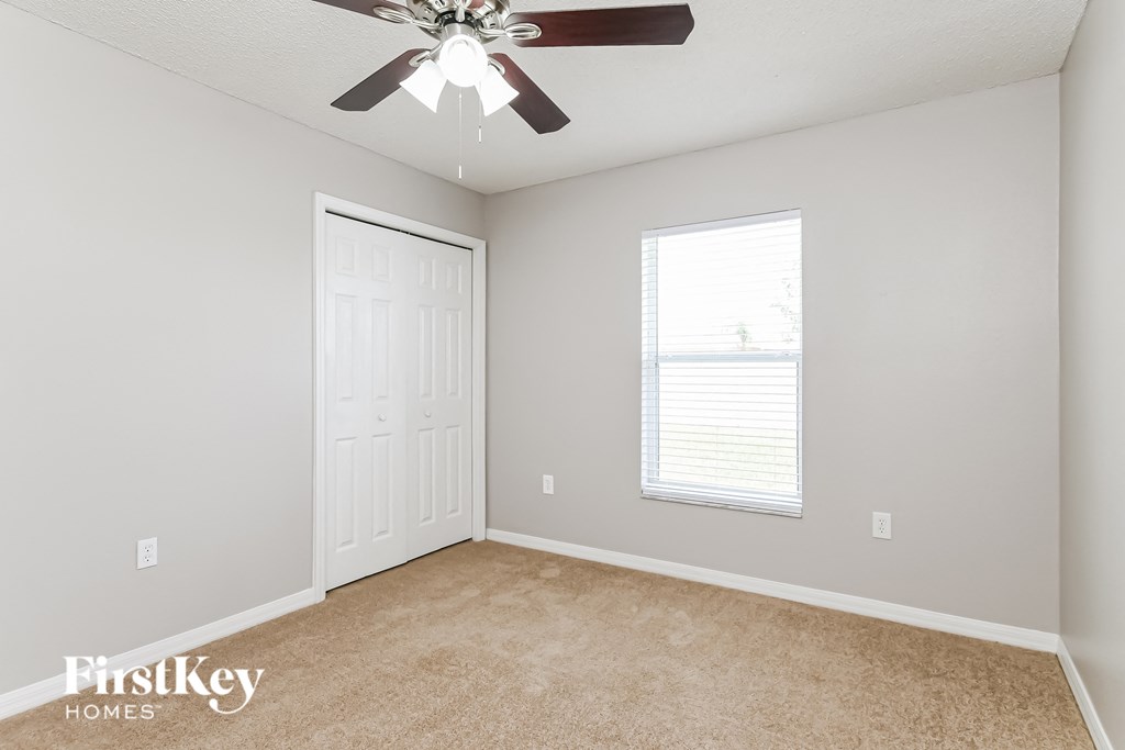 a bedroom with a ceiling fan and a closet