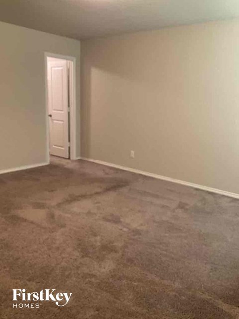 a carpeted living room with a white door and a gray carpet