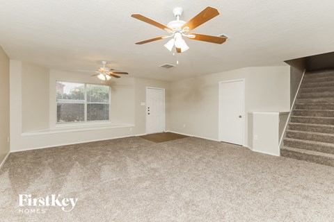 a living room with a ceiling fan and a staircase