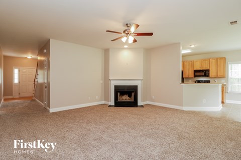 A spacious living room with a fireplace and a ceiling fan.