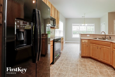 A kitchen with a black refrigerator and wooden cabinets.