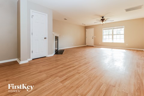 A spacious room with wooden flooring and a ceiling fan.