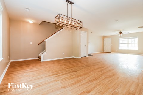 A large empty room with wooden floors and a staircase.